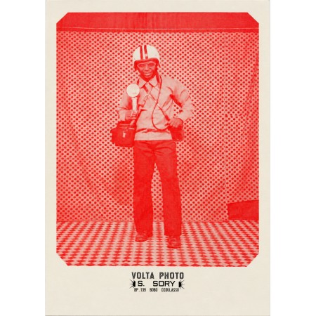 Póster de Sanlé Sory, un hombre con casco de moto y gafas ante el fondo de lunares del estudio Volta Photo