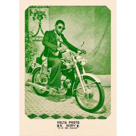 Póster de Sanlé Sory, un hombre de traje y gafas redondas sentado en una moto en el estudio Volta Photo