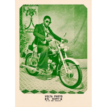 Póster de Sanlé Sory, un hombre de traje y gafas redondas sentado en una moto en el estudio Volta Photo